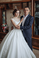 Fototapeta premium A man and a woman are posing for a picture. The man is wearing a suit and the woman is wearing a wedding dress. Scene is happy and celebratory