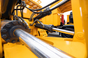 Pneumatic hydraulic piston for industry machinery technology. Concept chrome plated cylinder shaft of yellow bulldozers, tractors, excavators for lifting