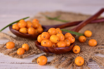 Ripe sea buckthorn berries in a wooden spoon.Close-up.
