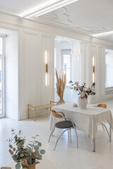 bright interior design of spacious living room with white walls and decorative unique historical moldings on ceiling stylish modern furniture in warm colors without people daylight through the windows