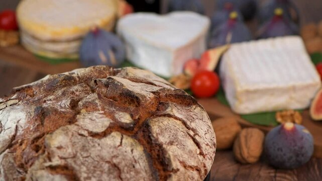 Selection of French cheeses from Normandy, AOP, Livarot, Neufchatel, Pont l'eveque, Pain de seigle, figs, walnuts, grapes, elderberry gelee. High quality 4k footage
