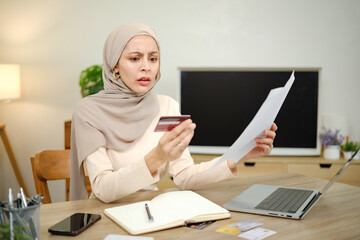 A woman is looking at a piece of paper with a credit card on it