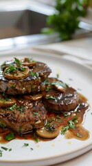 Juicy steak medallions topped with mushrooms and herbs served on a white plate, showcasing a delicious meal prepared in a contemporary kitchen setting