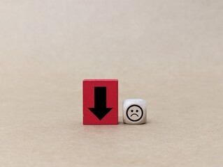 wooden doll, cube with down arrow and emotion. the concept of fluctuating spirits and feeling down