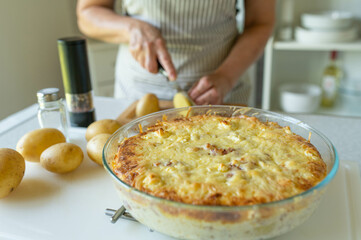Woman in the kitchen with a fresh baked potato casserole on kitchen counter