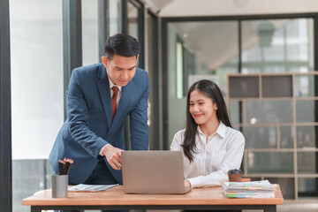 A man and a woman are sitting at a desk with a laptop in front of them. Concept of collaboration and teamwork