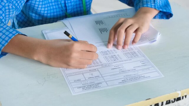 A student filling out each answer on an exam answer sheet, one by one. This footage captures the meticulous process of test-taking, ideal for educational projects, exam preparation, or showcasing. 4K