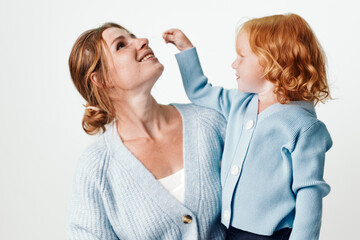 Happy mother and daughter smiling together against white background in a joyful family moment