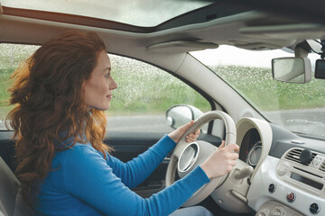 Young Woman Driving in a Car With Rain on the Windshield During a Cloudy Day