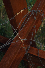 A close-up view of rusty metal anti-tank hedgehog intertwined with barbed wire