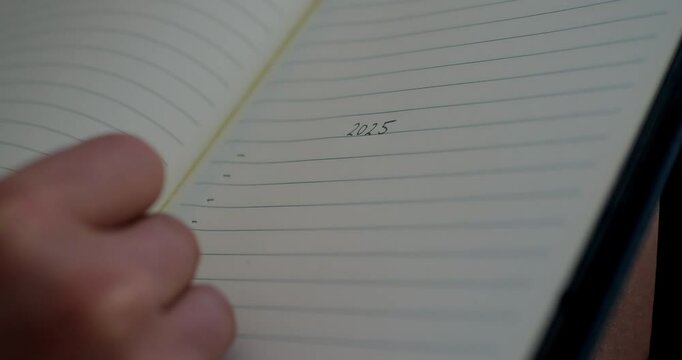 Closeup of writing 2025 goals on notepad