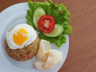 fried rice with egg and vegetables on white plate and wood background