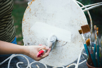 Painting an wrought iron chair outdoors, an eco-friendly re-use business.