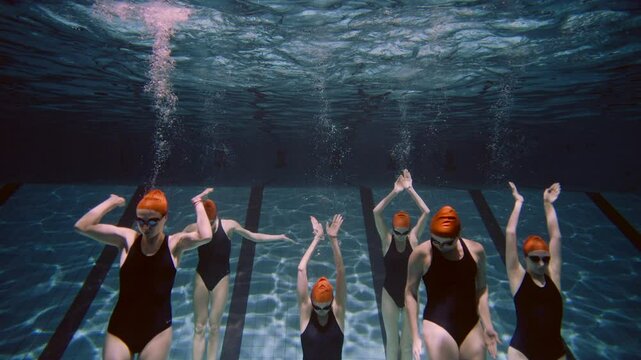 Six Women practicing synchronized swimming in the pool coming from the bottom
