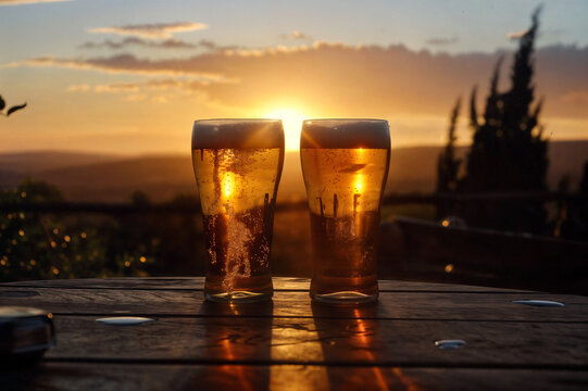Dos cervezas apoyadas en una mesa con el atardecer de fondo. 