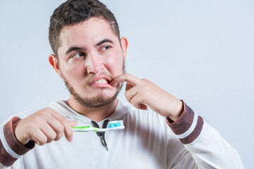 Young man with tooth sensitivity holding a toothbrush isolated. Man suffering from gum pain holding...