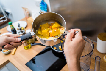 Chef at the kitchen preparing pumpkin porridge with tofu and vegetables