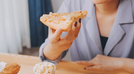 Cropped image of woman holding pizza slice at restaurant