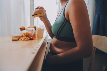 Binge eating disorder concept with woman eating fast food burger, fired chicken , donuts and desserts