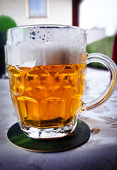Cold, amber beer with white foam in a glass mug