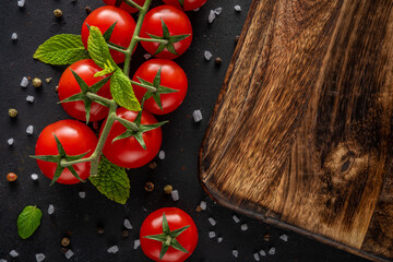 Fresh cherry tomatoes on a black background with spices. Food background. Top view.