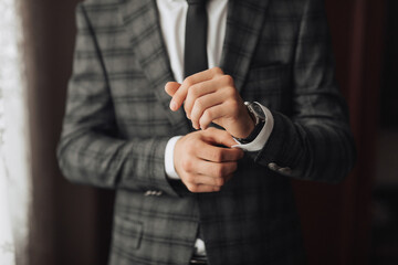 A man in a suit is adjusting his tie. Concept of formality and professionalism, as the man is dressed in a suit and tie