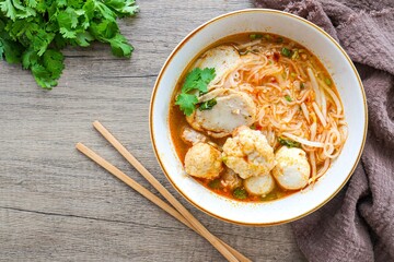 Thin rice noodles soup  with meatball in a ceramic bowl  with chopsticks on wooden backgroud 