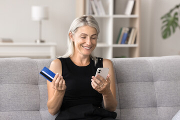 Mature woman spend money on-line, using credit card and cellphone to make payment through e-banking application, buying goods via retail marketplace services. Modern tech, remote electronic shopping