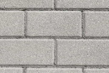 Gray brick pavement texture. Even blocks pattern. Brick flooring. Outdoor sunny texture. Walkway background. Brick pattern. Closeup construction. Empty copy space blocks.