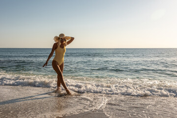 Gorgeous fashion model in swimsuit on a sand beach. Summer holiday concept.