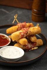 Closeup on fried mozzarella sticks with bacon and sauces