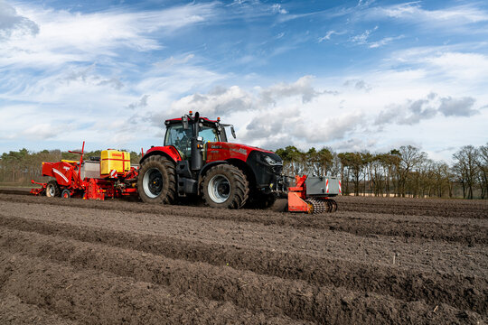 Kartoffelanbau - moderner Case-IH Traktor beim Legen von Kartoffeln mit einer Grimme Kartoffel-Legemaschine.