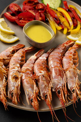 Fried shrimps on plate with fresh vegetables and lemon slice. Seafood background.