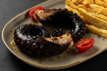 Sea delicacy grilled octopus with potatoes. Dishes on a dark decorated background.