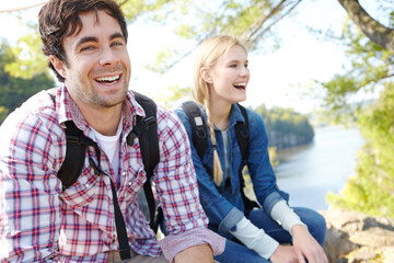 Portrait, relax or happy couple hiking by river for travel, outdoor adventure or journey in nature with smile. Laugh, resting or people in forest on holiday vacation, fun trip or lake to explore park