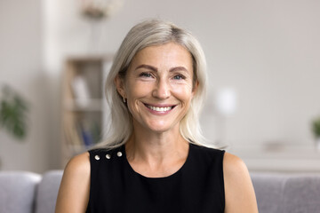 Head shot portrait pretty blonde woman looking at camera, sits alone on sofa photoshooting, enjoy...