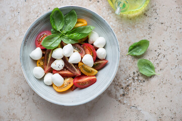 Grey plate with italian caprese salad on a beige granite background, horizontal shot, view from above