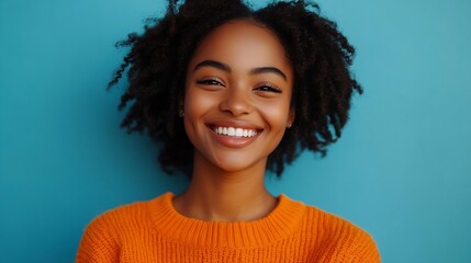 Happy emotions concept Positive dark skinned beautiful young woman laughs poisitively looks aside with carefree face expression wears casual orange sweater isolated over blue studio ba : Generative AI