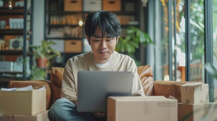 Asian business men sit on sofa use laptop computer checking customer order online shipping boxes at home