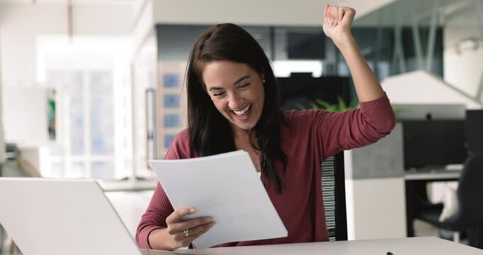 Businesswoman reading and celebrating positive news at her workplace. Project approval, received notification about promotion or salary increase, successful audit results, gets award or recognition