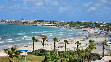 Beach in Acre, Israel with Blue Water, Waves, Flag Trees, and View of the Old City