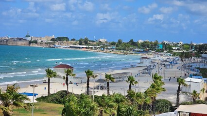 Beach in Acre, Israel with Blue Water, Waves, Flag Trees, and View of the Old City