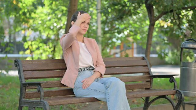 Young Woman with Headache Sitting in Park