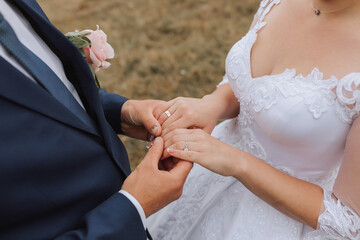 A bride and groom are getting married and the bride is wearing a white dress. The groom is holding the bride's hand and they are both smiling