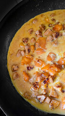 Fried eggs with mushrooms and yellow tomatoes in a frying pan. Home cooking.