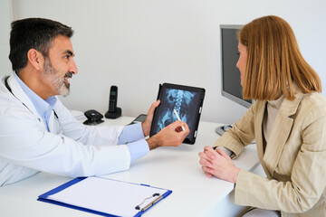 Doctor explaining x-ray to his female patient before a surgery for a broken hip. Healthcare and...