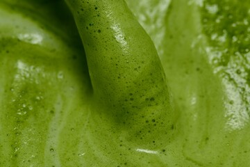 A close-up image of green tea with a smooth, frothy texture. The vibrant green color and visible air bubbles on the surface highlight the freshness and quality of Movement of bubbles on the tea 