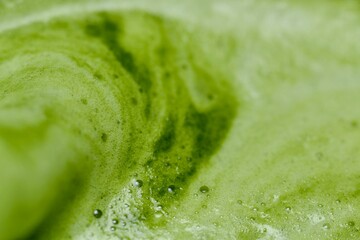 A close-up image of green tea with a smooth, frothy texture. The vibrant green color and visible...