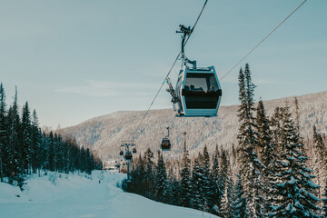 gondola ski lift in mountain ski resort, winter day, snowy spruce forest