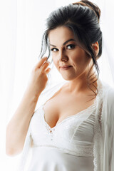 A woman is posing for a picture with her hand on her head. She is wearing a white dress and a veil. Concept of elegance and sophistication, as the woman is dressed for a special occasion